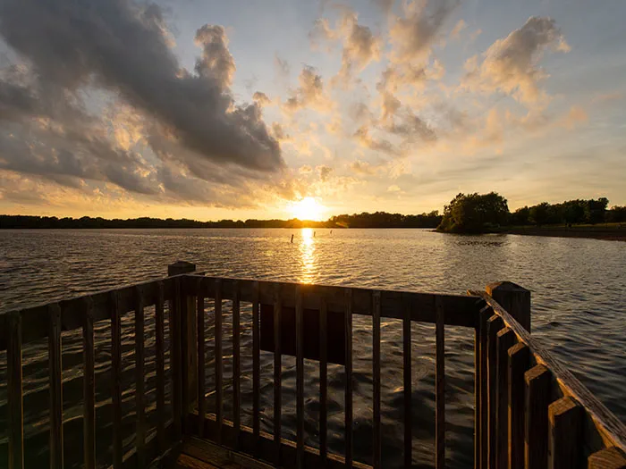 sun setting over water at end of fishing pier