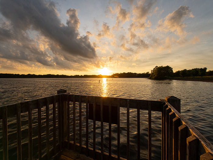 sun setting over water at end of fishing pier