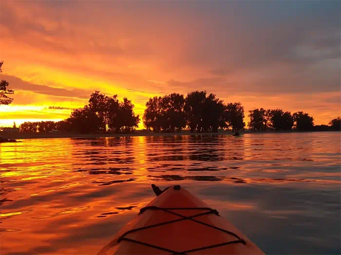 tip of kayak on water at sunset