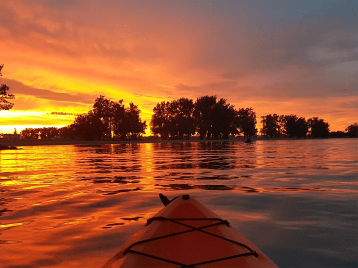tip of kayak on water at sunset