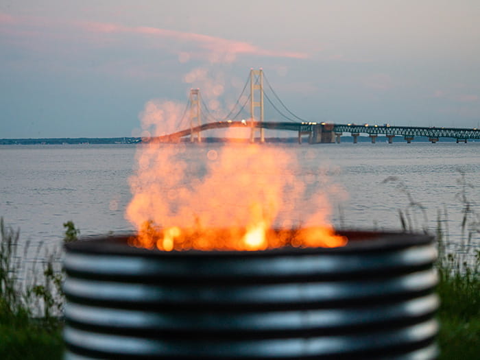 A campfire burning with the Mackinac Bridge in the background