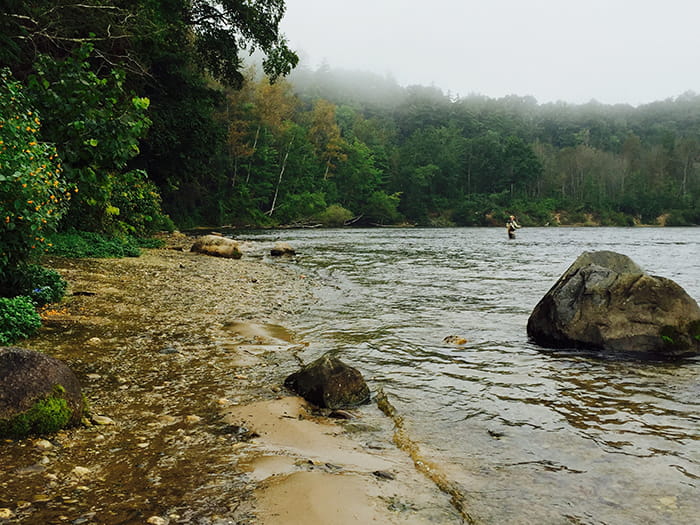 angler in river with rocks
