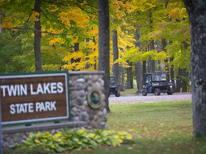 ORVs riding on park with park sign
