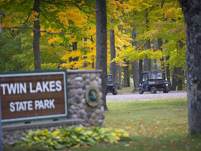 ORVs riding on park with park sign