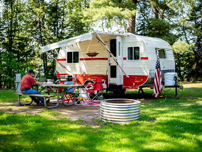 retro camper in campsite with a man at a picnic table