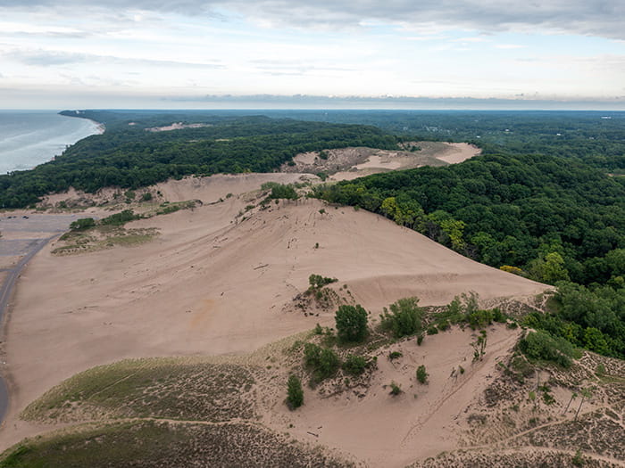 An aerial view of sand dunes, wooded areas and Lake Michigan