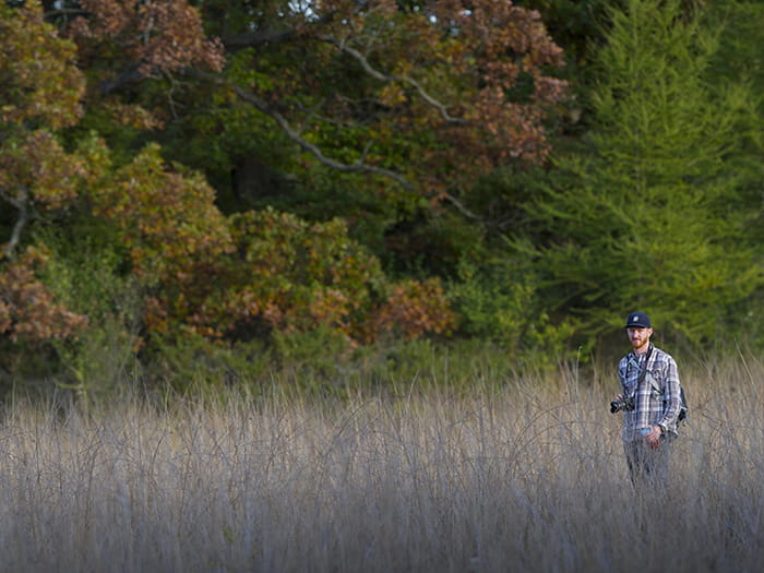 photographer standing along treeline