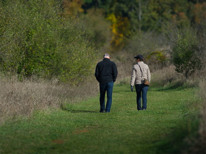 two visitors walking along grassy trail