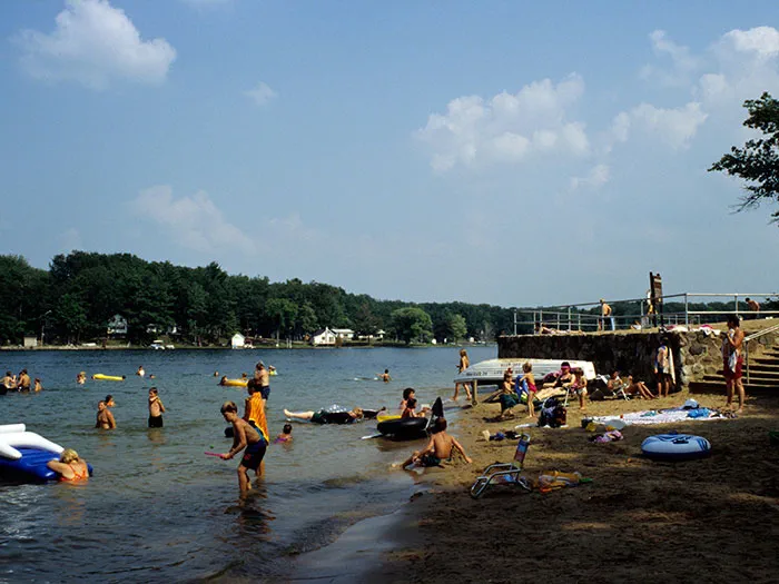 people wading in water and sitting on sandy beach