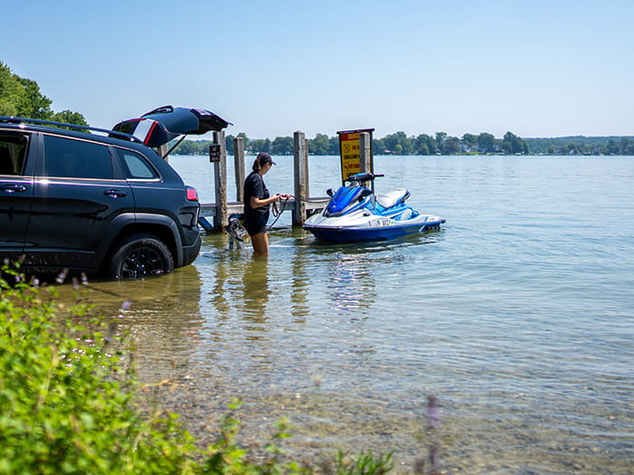 Woman wading in the water to launch a jet ski at Yankee Springs recreation area