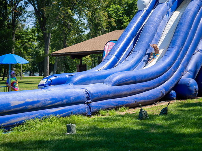 A young child sliding down a large, blue inflatable slide