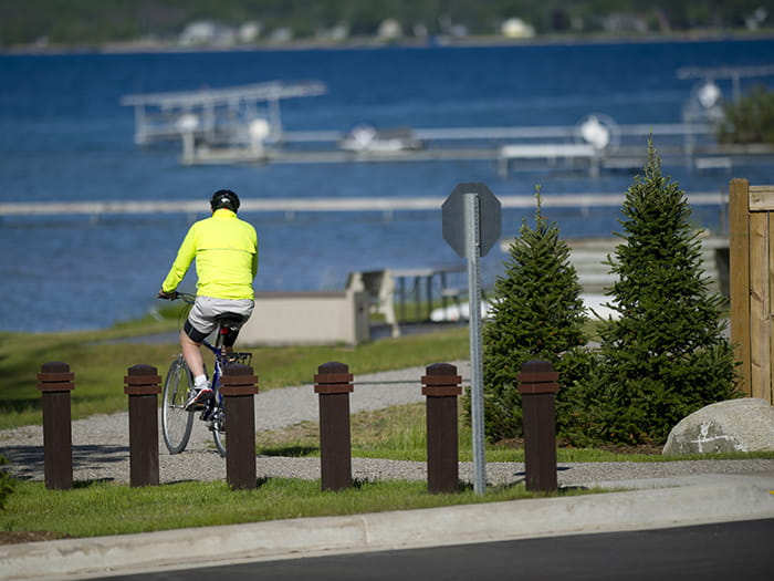 A cyclist with a yellow jacket bikes along a waterfront area