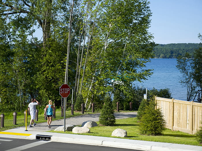 People walking on a paved trail with a waterfront in the distance