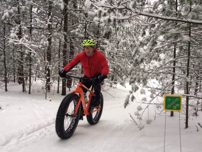 A person riding a fat tire bike on a snowy pathway