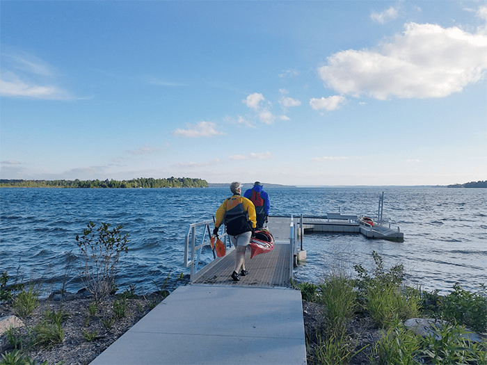 Paddlers walking down access point with kayaks