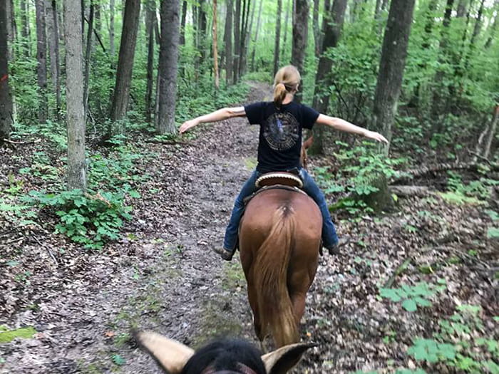 A young person riding a horse viewed from behind