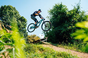 a mountain bike jumping off ramp along trail