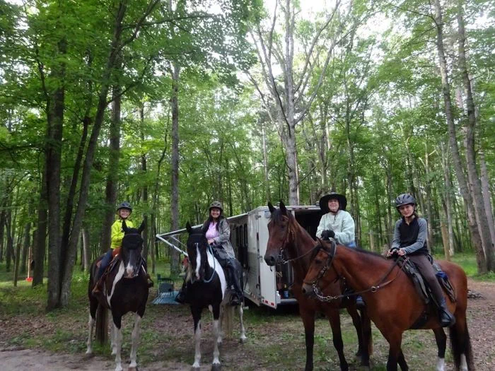 The horseback riders next to their trailer