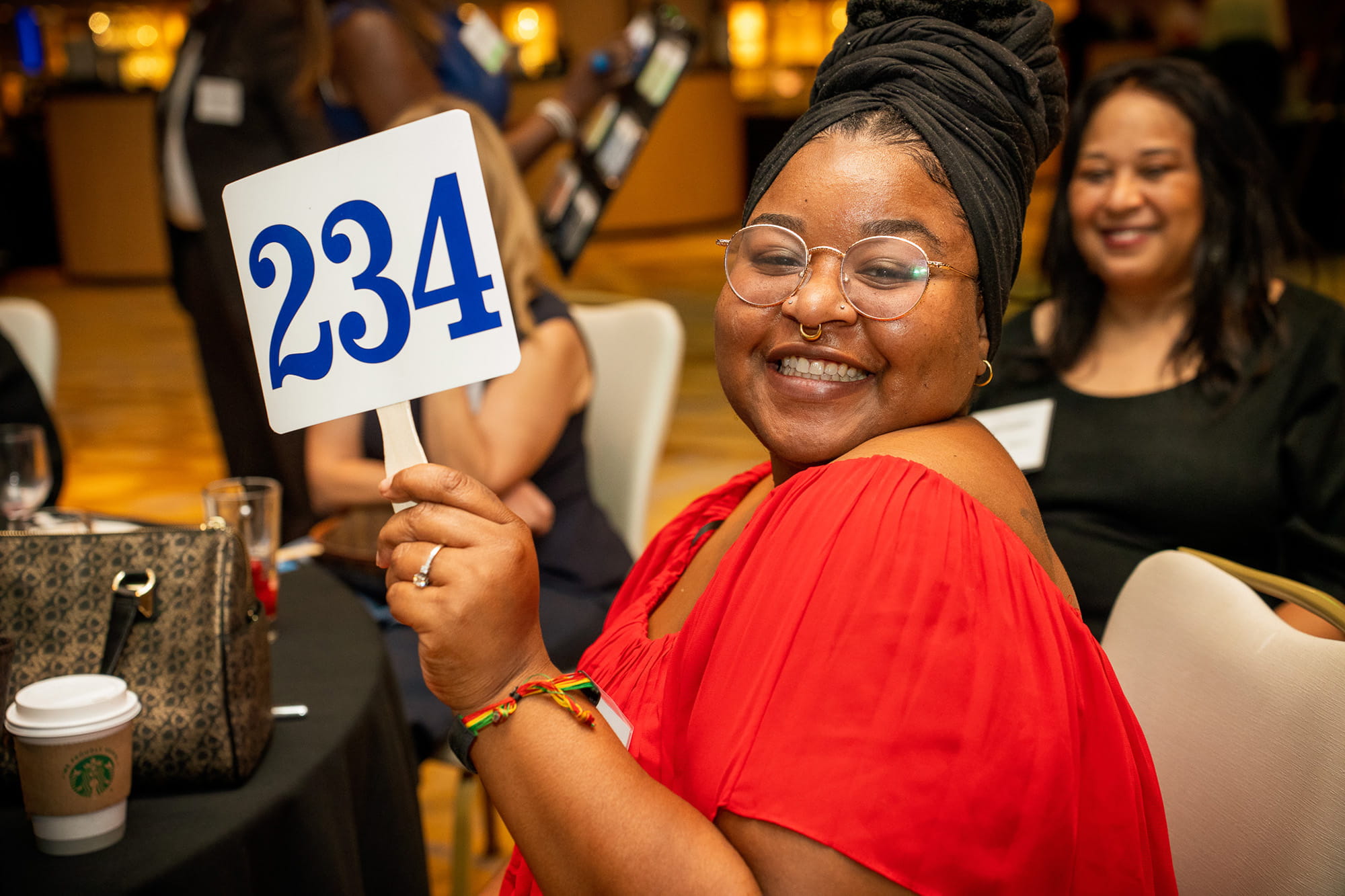 A happy smiling Gala attendee raises her paddle to donate