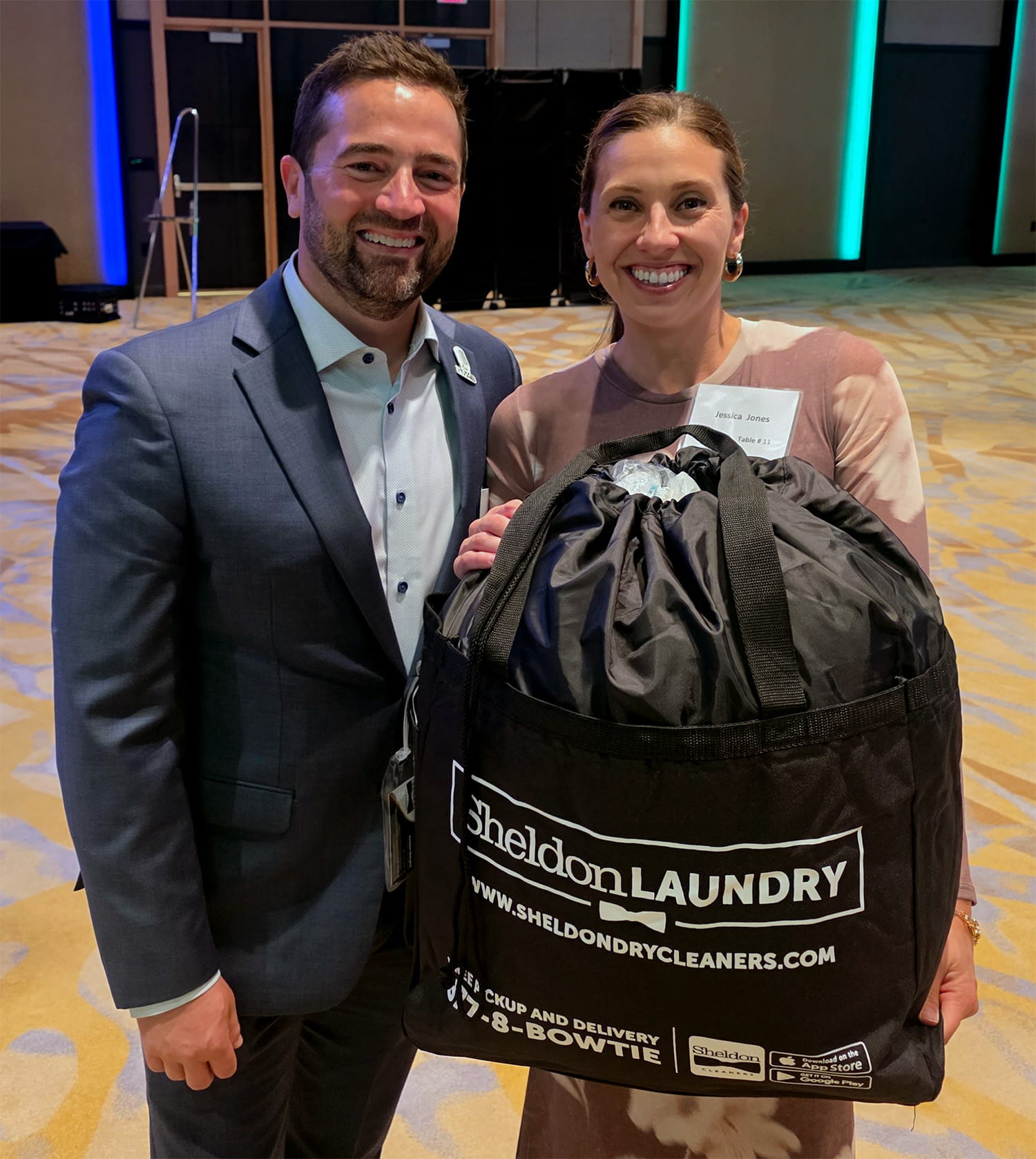 Two happy raffle winners smile as they hold up their winnings, a subscription for Sheldon Laundry 