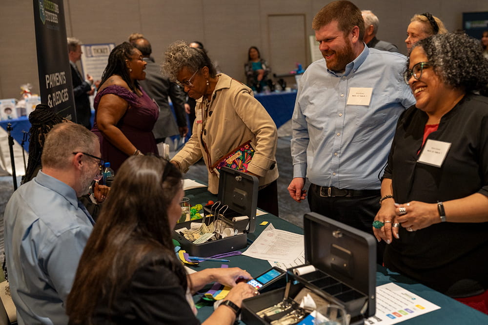Gala attendees visit the finance table to purchase raffle tickets to bid on artwork and raffle baskets. 