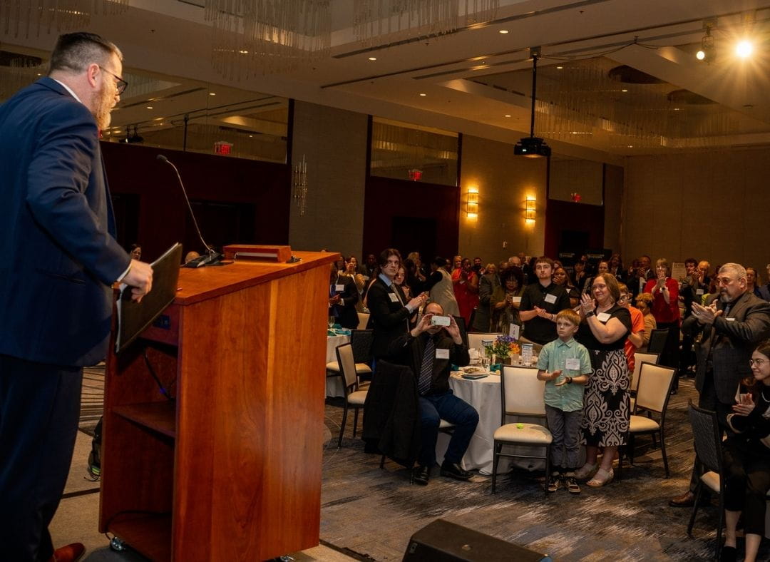 Keynote speaker stands at podium and receives a standing ovation.