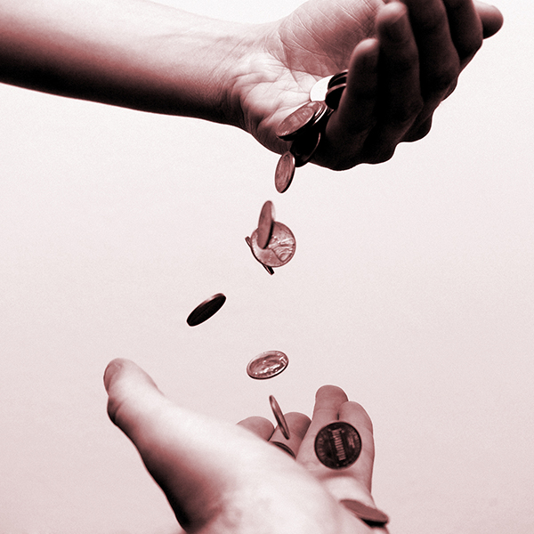A person pouring pennies into the hands of a second person
