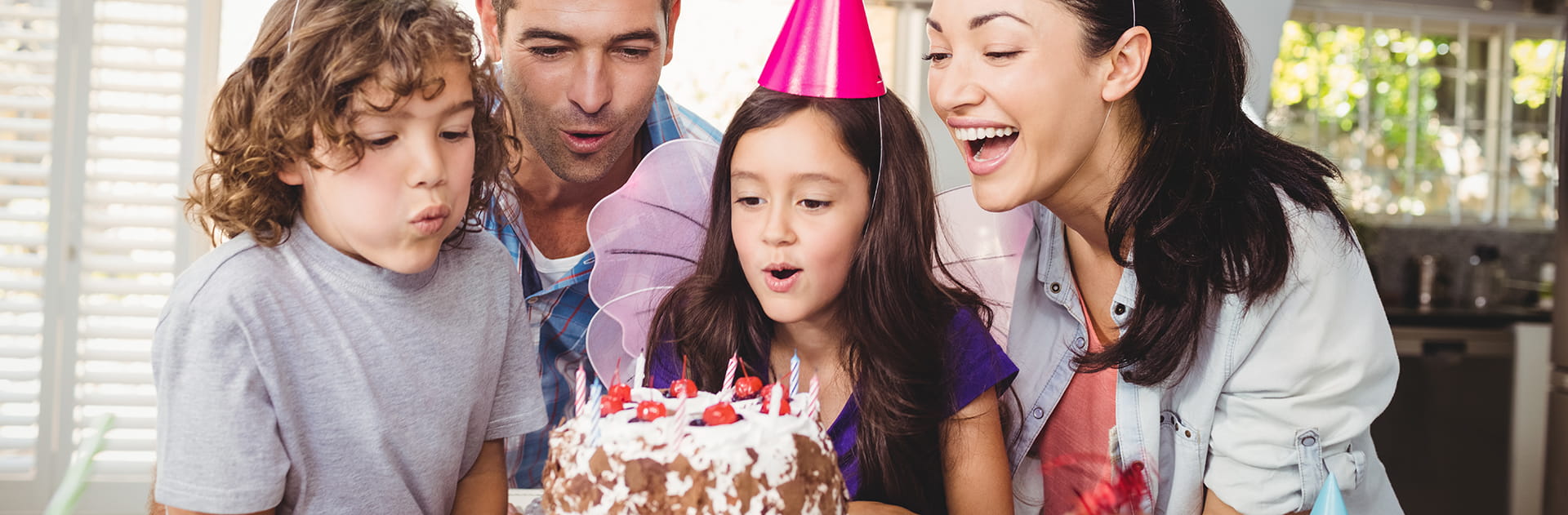 Young girl surrounded by family blowing out candles on a birthday cake