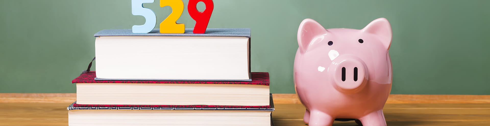 Piggy bank on desk next to stack of school books