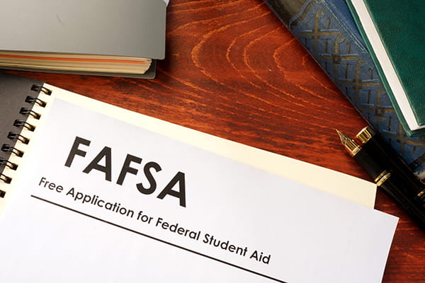 FAFSA materials surrounded by books on top of a desk