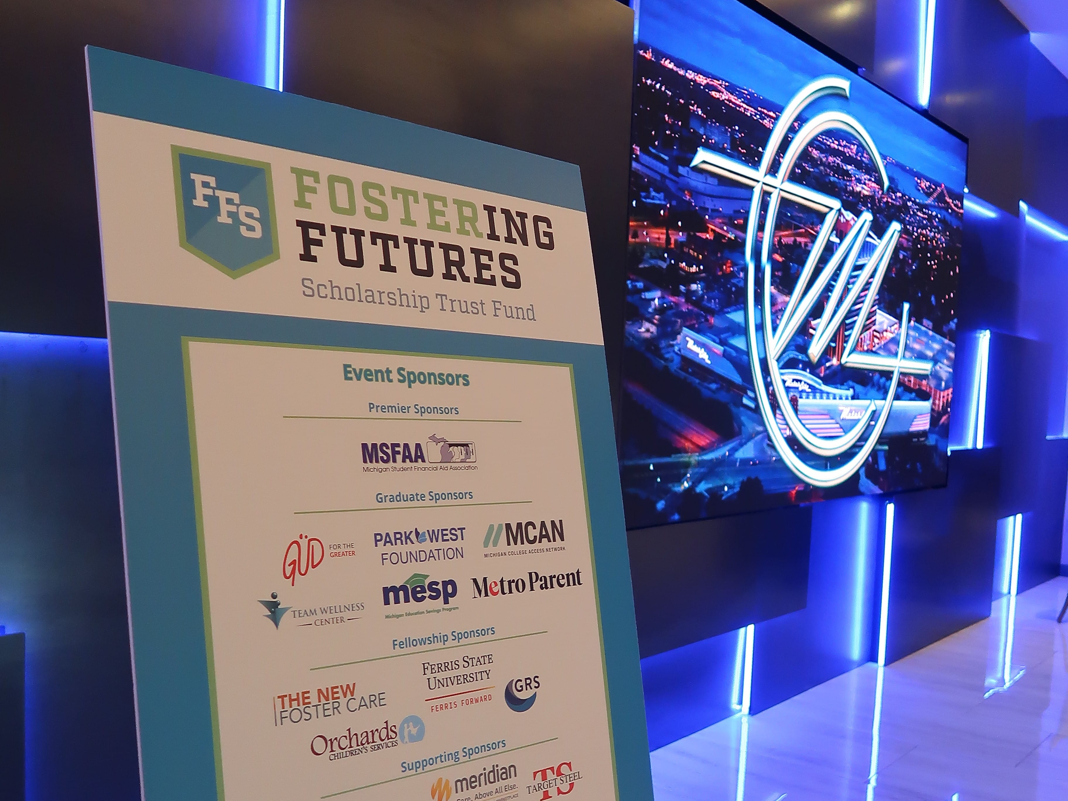 Event sponsor board with glowing Motor City Casino logo sign in the background