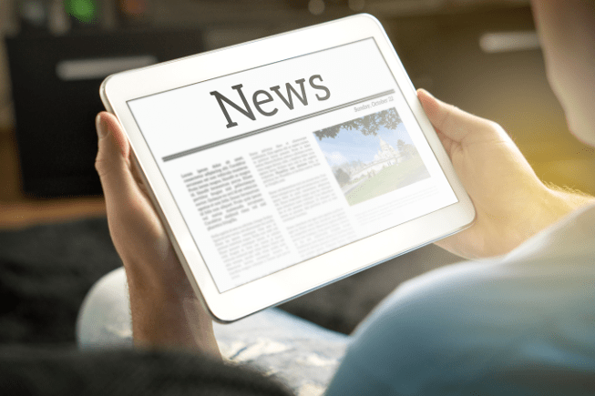 Person holding a tablet showing a newspaper on the screen