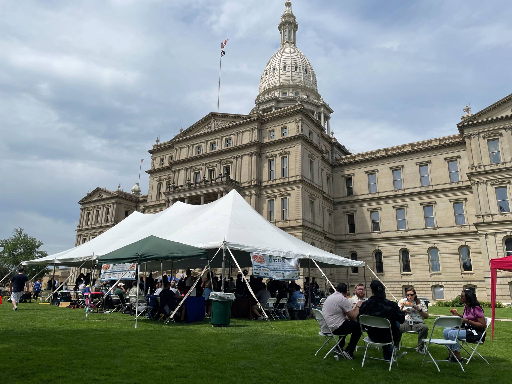 Large, white party tent set up on Michigan Capitol Lawn filled with people
