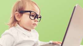Photo of a toddler wearing black rim glasses in front of a laptop