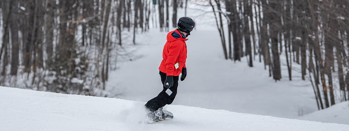 Snowboard heading down tree-lined run