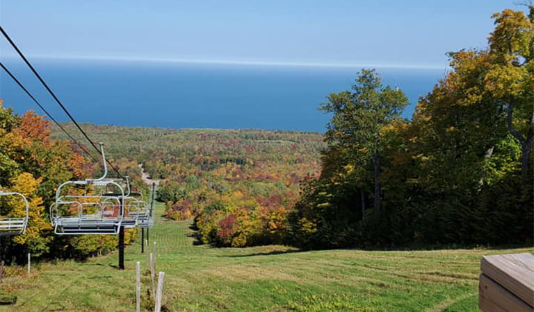 Chairlift at the Porkies with fall color on trees and Lake Superior in background