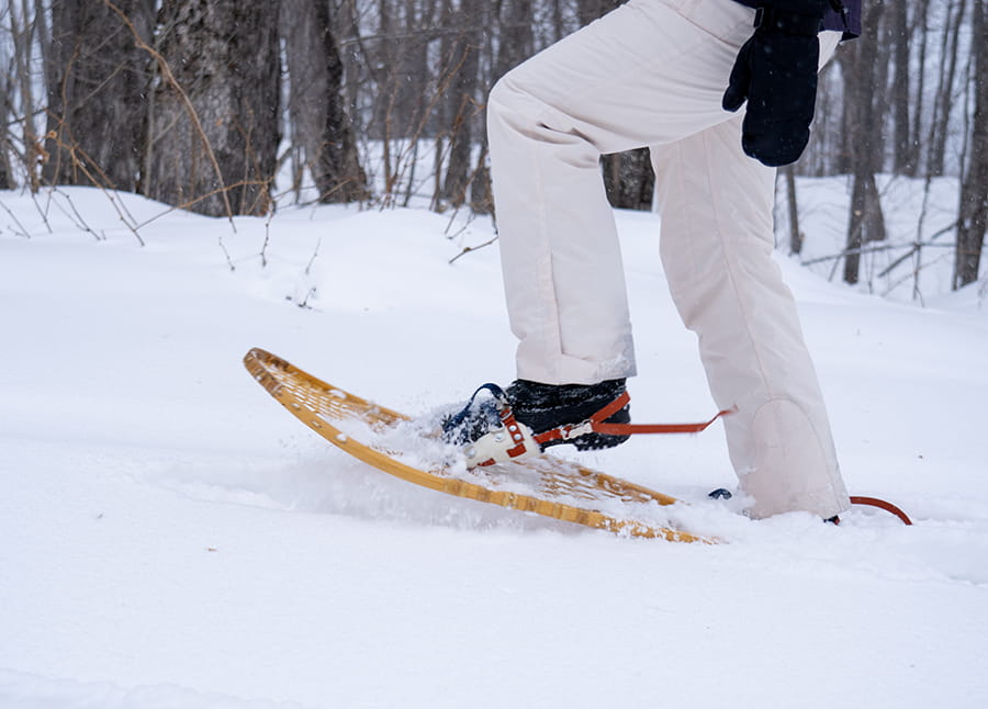 person stepping down into snow with snowshoe