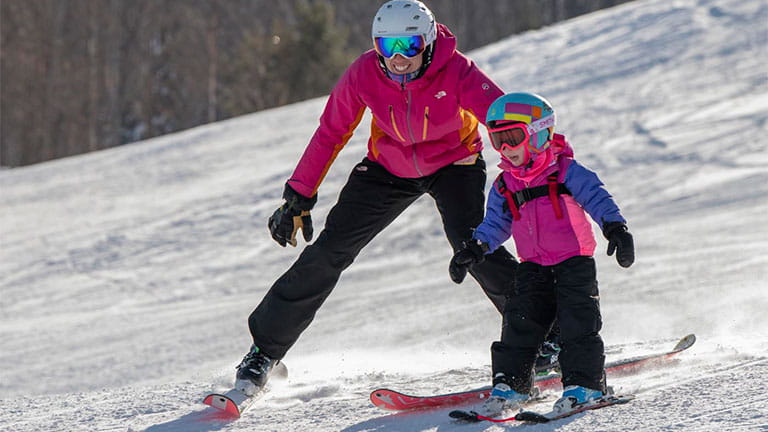A skier teaches a child how to ski