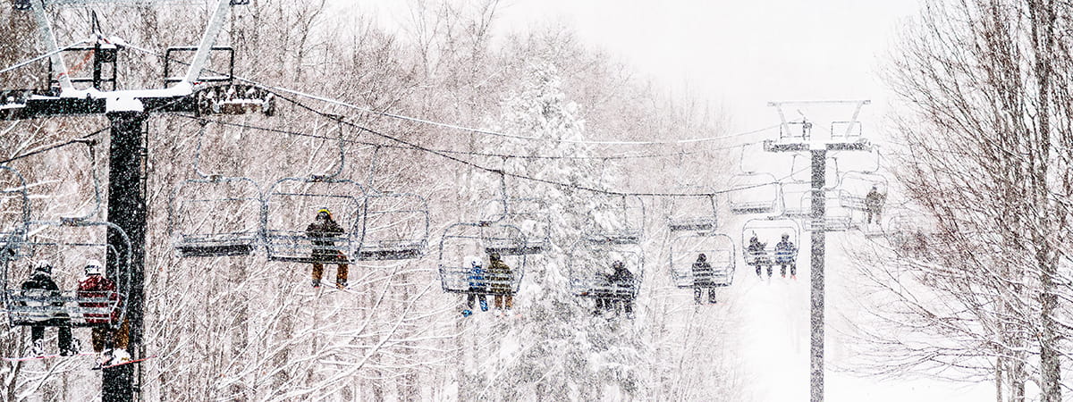 people riding the triple chairlift with snow coming down