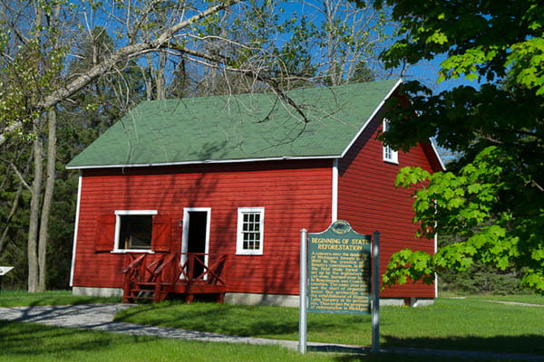 Photo of a red bard with a historical marker posted in the lawn near it.