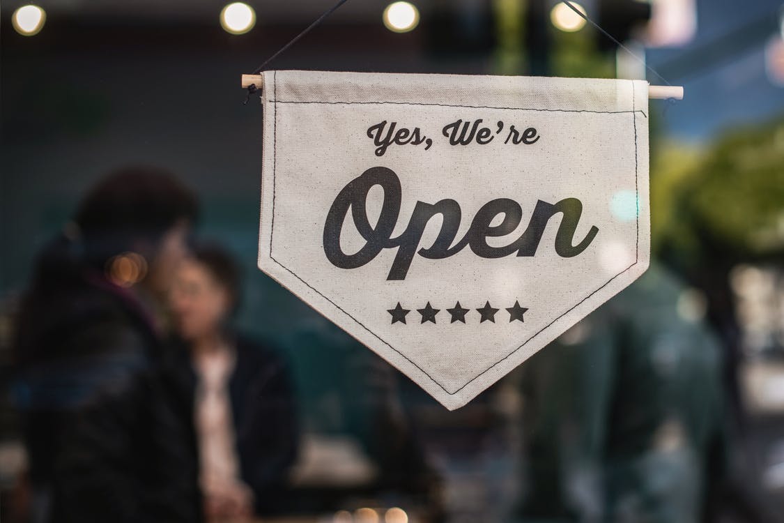 Sign hanging on glass window saying, "Yes We're Open."