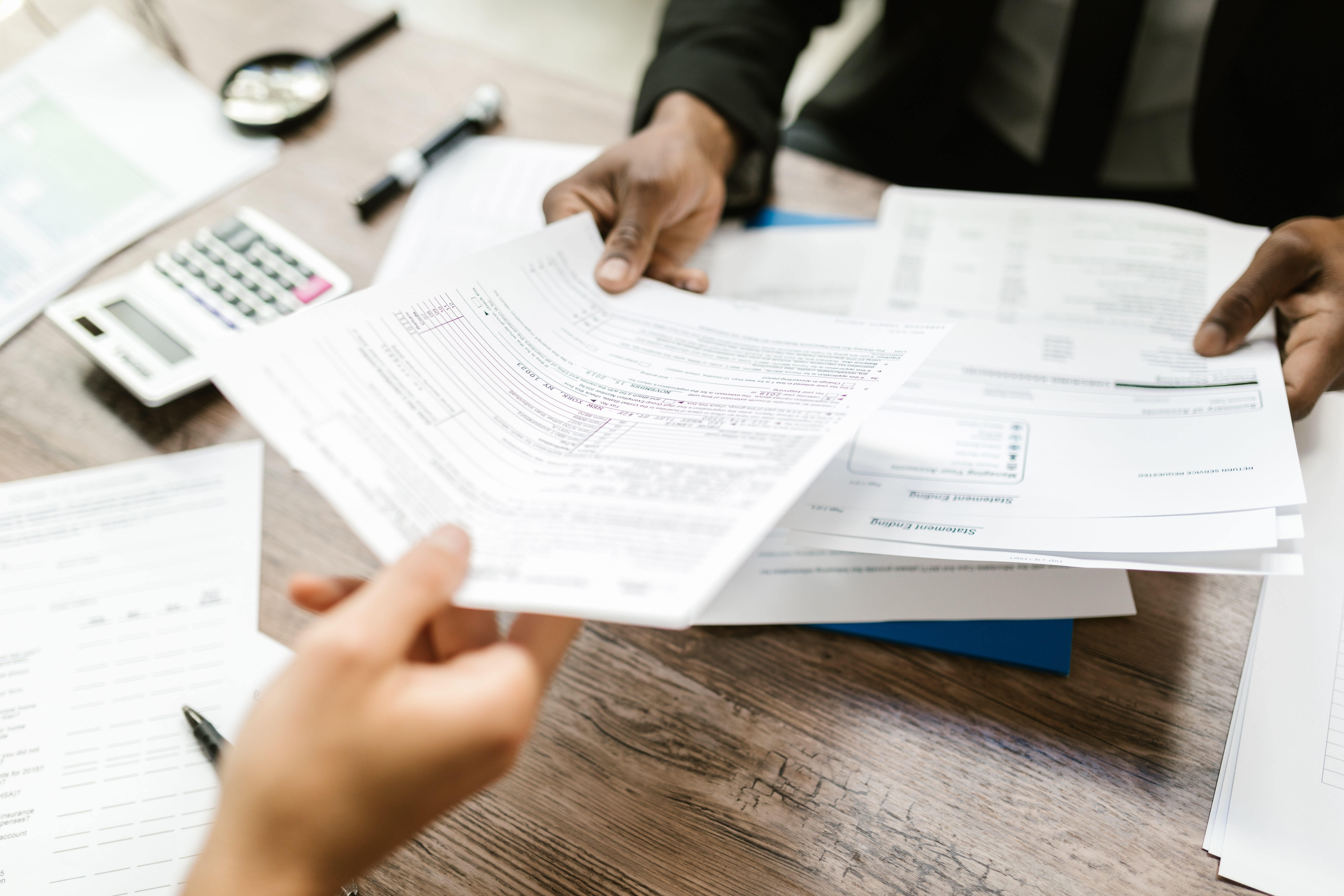 Person handing tax papers to another person.