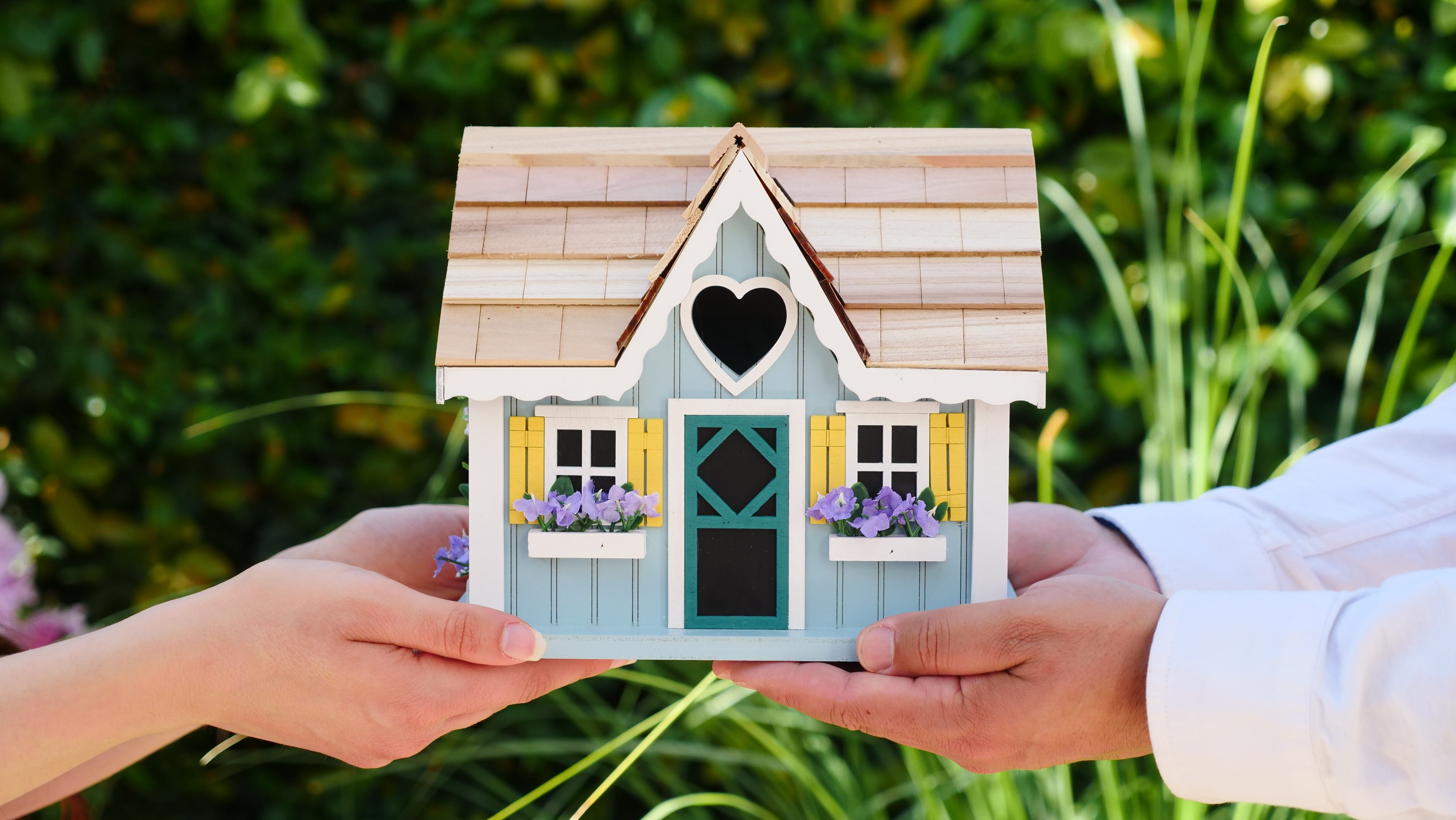 Photo of a small house being held by two people.