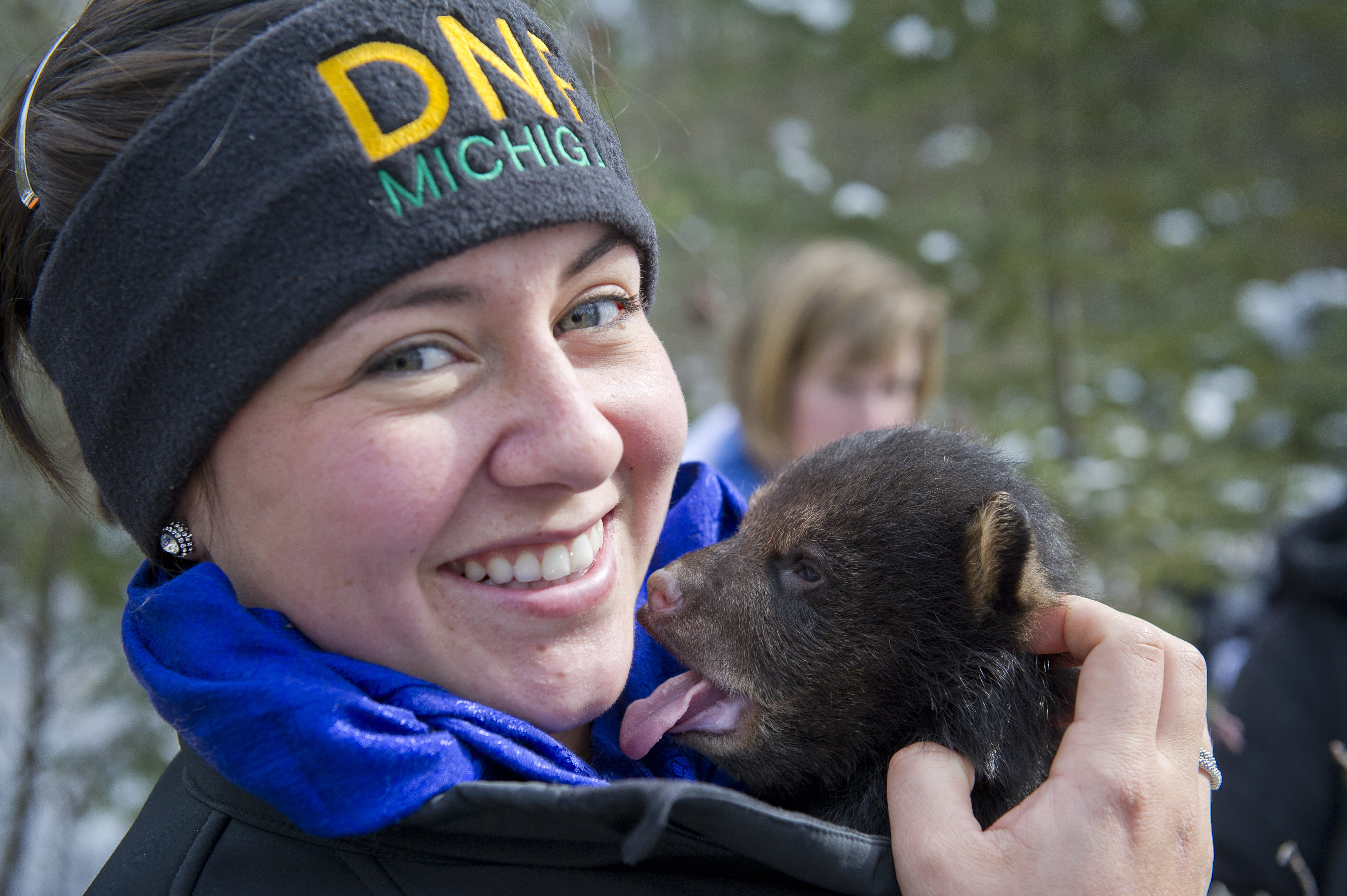 Photo of a parks staff employee holding a small bear cub.