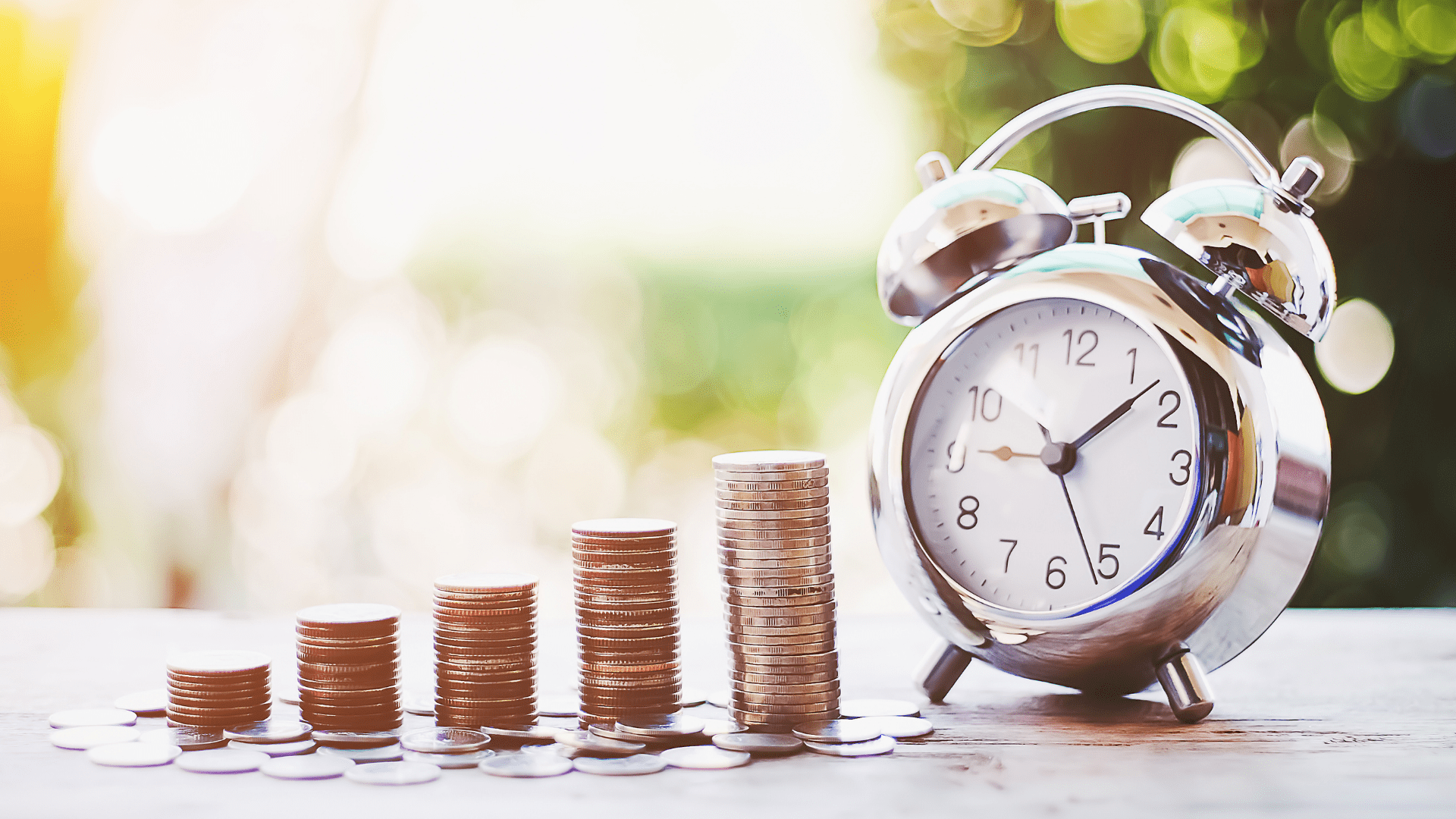 Image of coins in stacks getting larger in size as they move towards a clock.