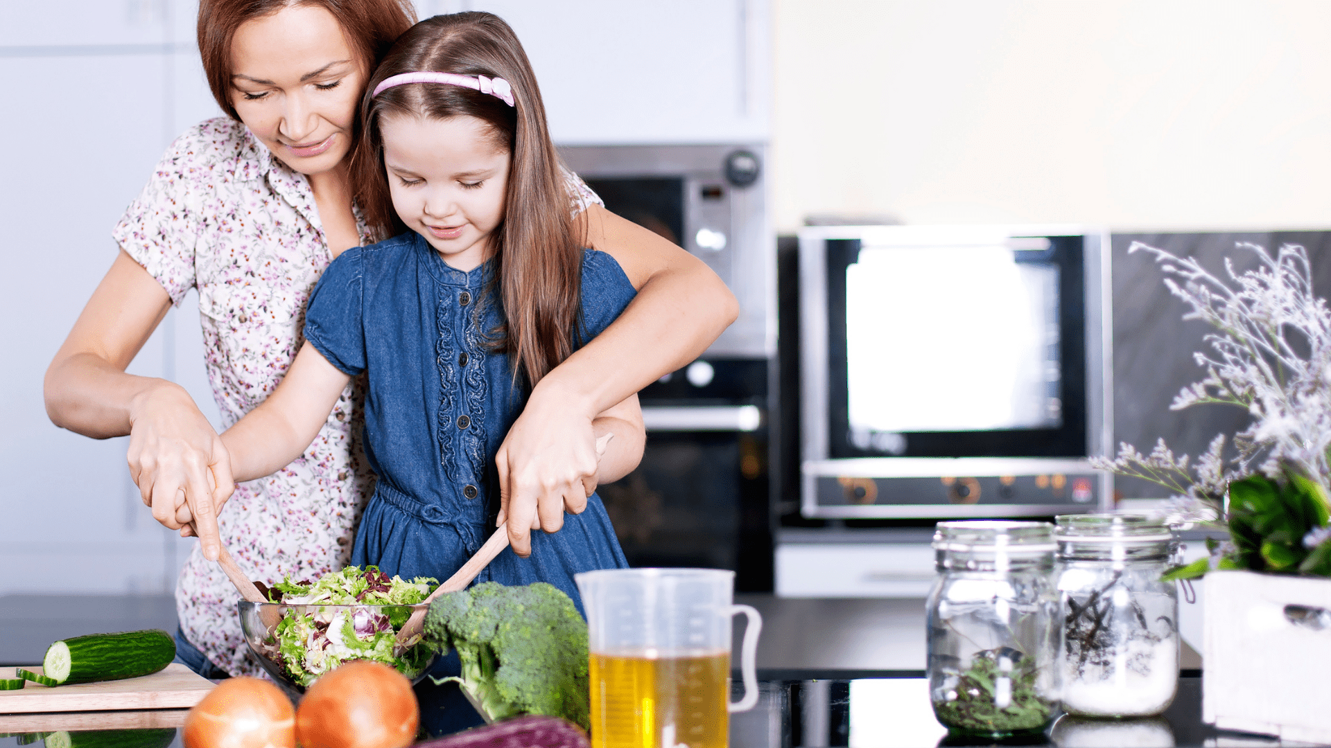 A woman and child cooking a healthy meal.