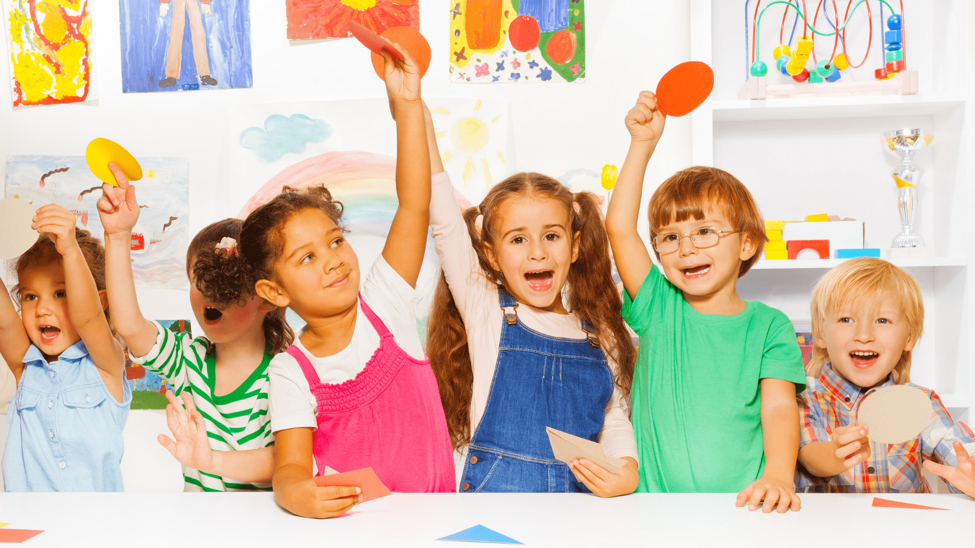 Six kids sitting at a table doing crafts.