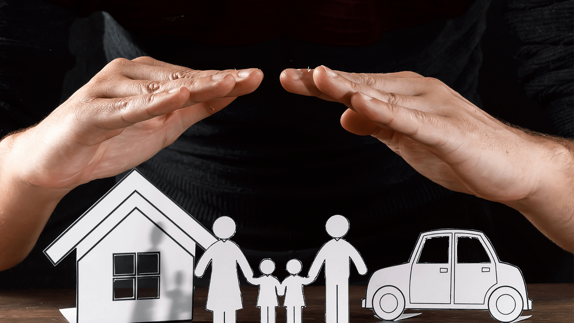 Image of a persons hands over a paper house, people and car acting as a safety net.