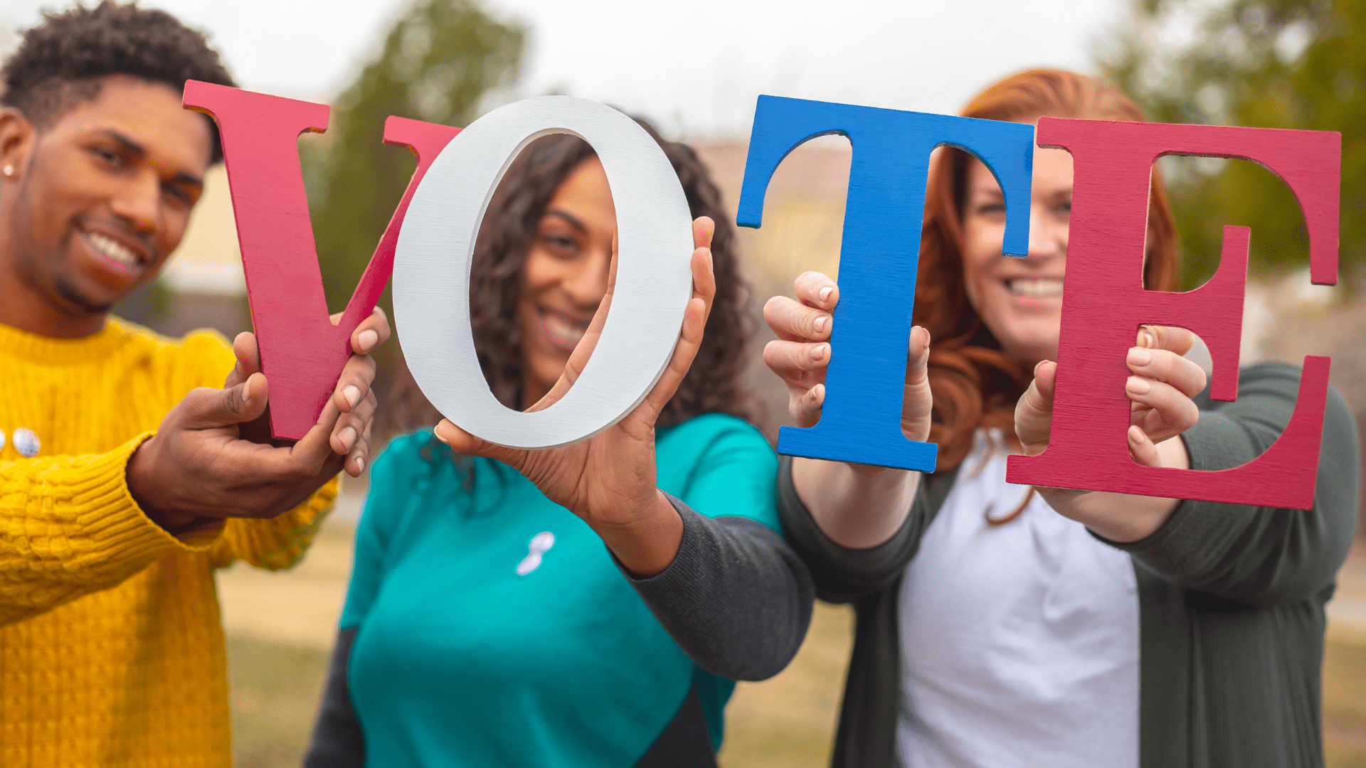 Image of four people holding up the letters to spell the word vote.