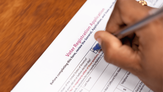 Closeup of hand filling out voter registration application